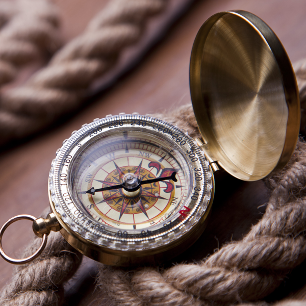 An open compass sitting on top of a thick rope.